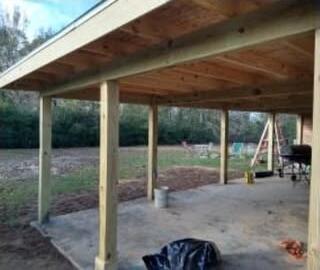 New wood-framed covered patio with posts and rafters over a concrete slab